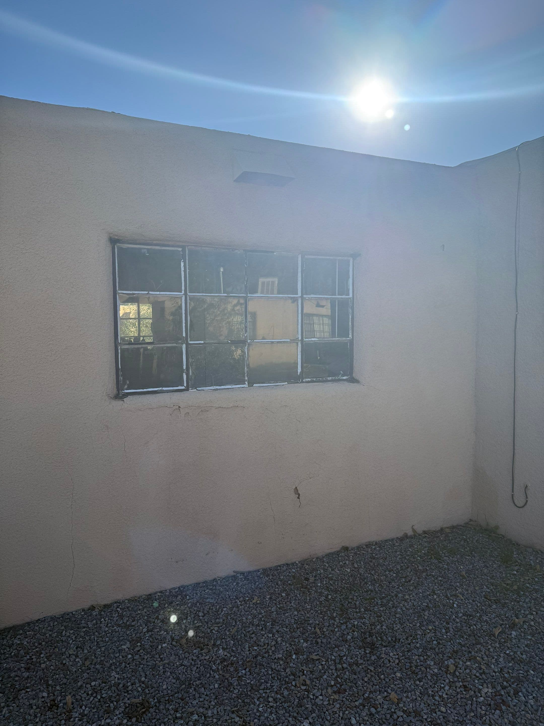 Before the install — original 1960s-era steel-frame multi-pane single-pane window on the tan stucco exterior