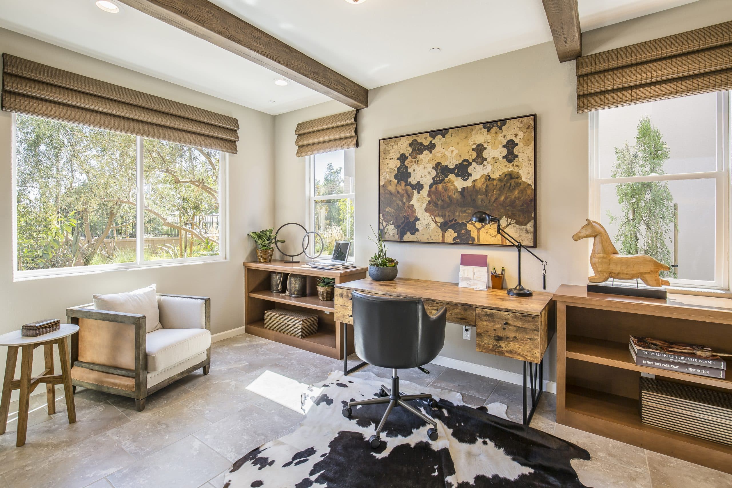 Home office with white-frame Anlin double-hung windows on two walls, beamed ceiling, and a desk facing the view